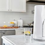Nanotecnología en filtros de agua: foto realista de una cocina moderna minimalista, con un purificador de agua de encimera tipo Aqua Nano CTU-500. Luz natural, colores blancos y azules, estilo editorial para blog de tecnología.