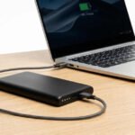 Power bank USB-C de alta capacidad conectado a un portátil ultrabook sobre una mesa de trabajo