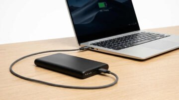 Power bank USB-C de alta capacidad conectado a un portátil ultrabook sobre una mesa de trabajo