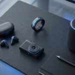 Gadgets con IA integrada: auriculares, anillo inteligente, cámara y altavoz sobre superficie oscura